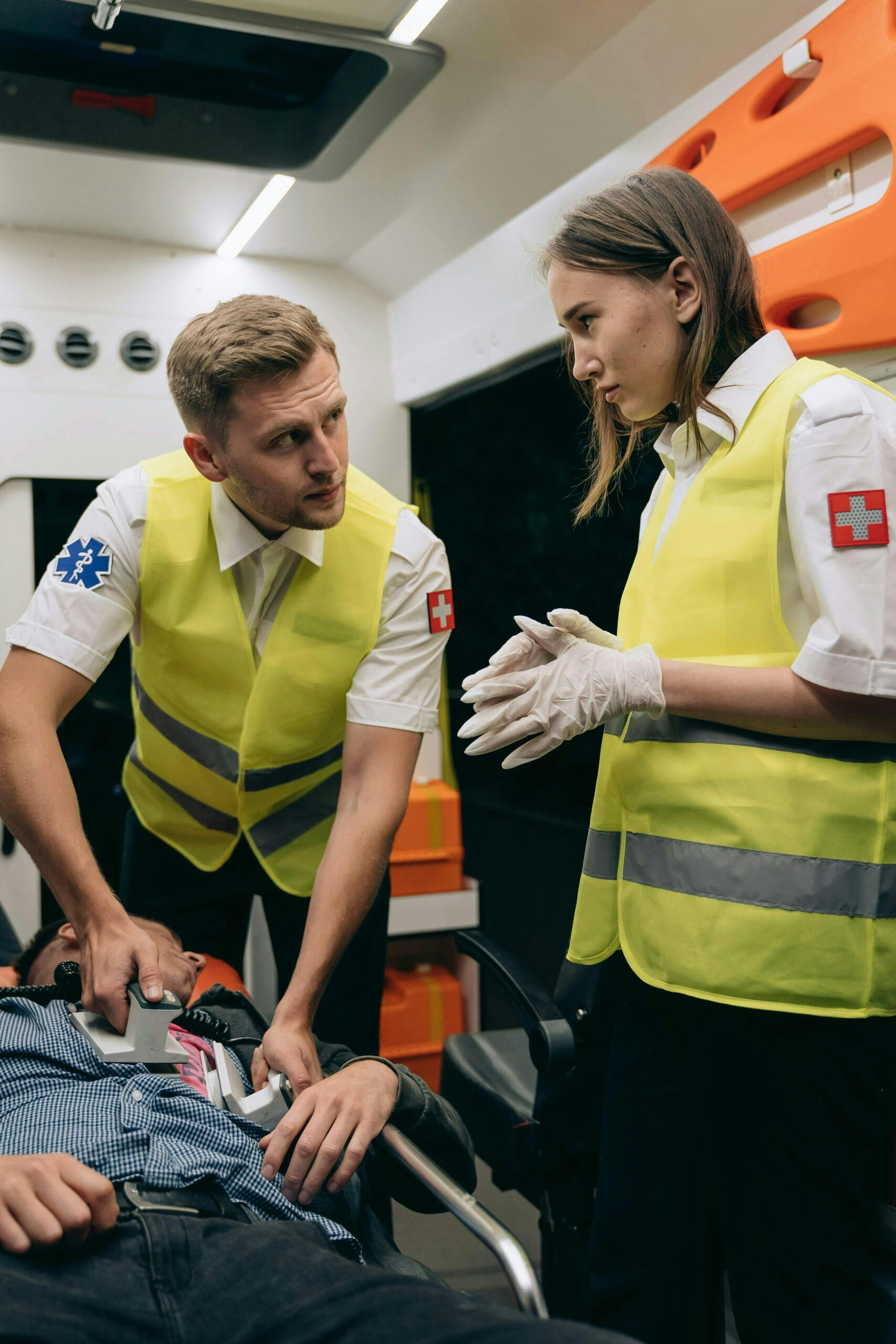 Two paramedics assist a patient inside an ambulance, showcasing emergency medical response.