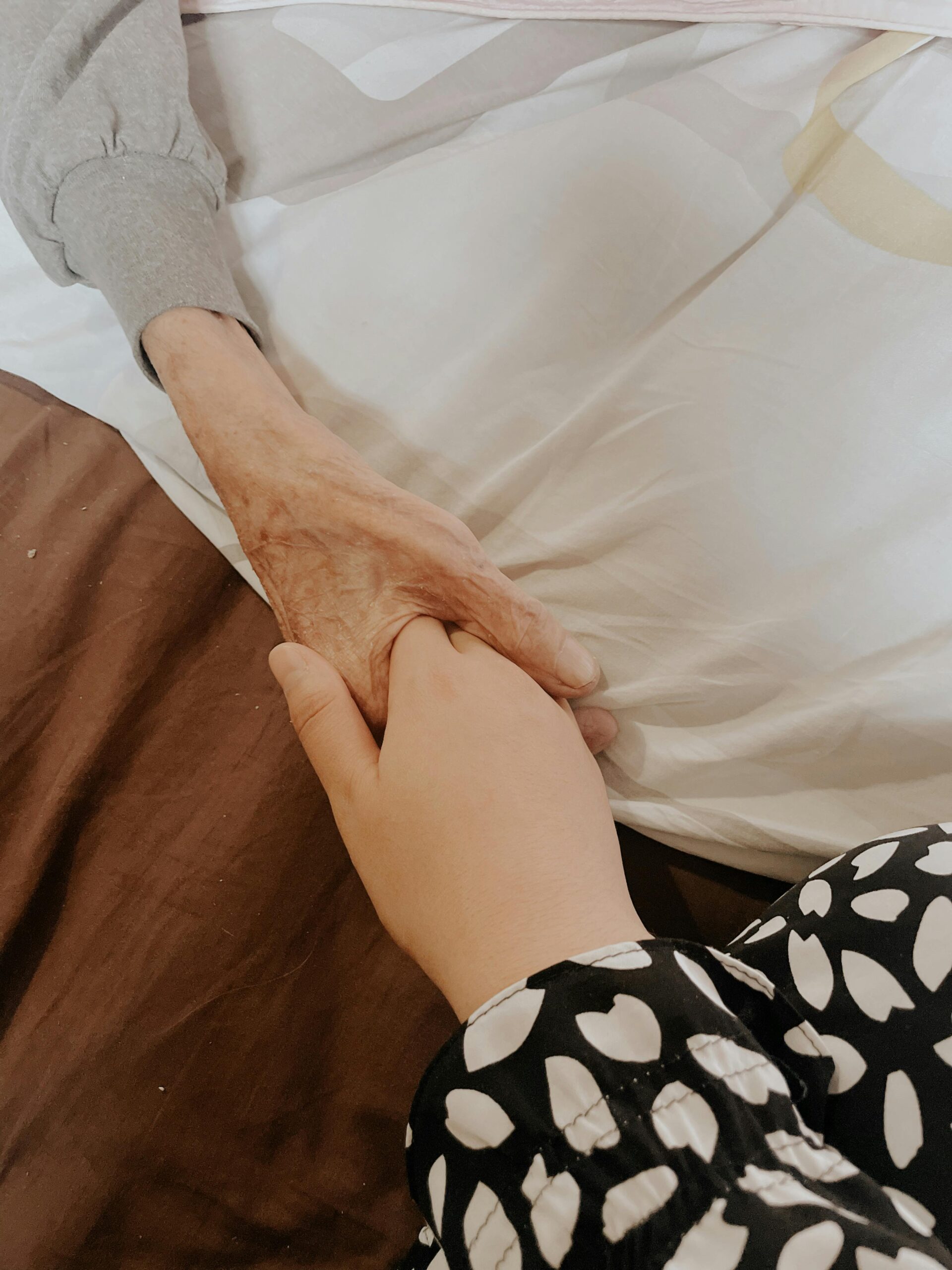A touching moment of an adult holding a senior's hand, symbolizing love and support.