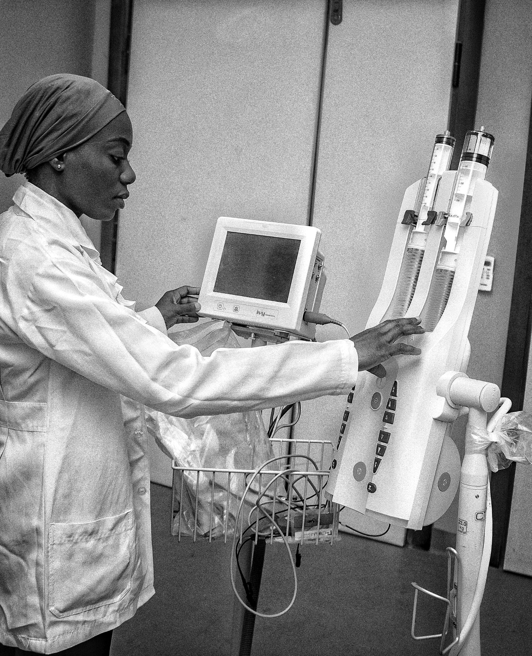 A focused healthcare worker operates advanced medical machinery in a clinical setting.