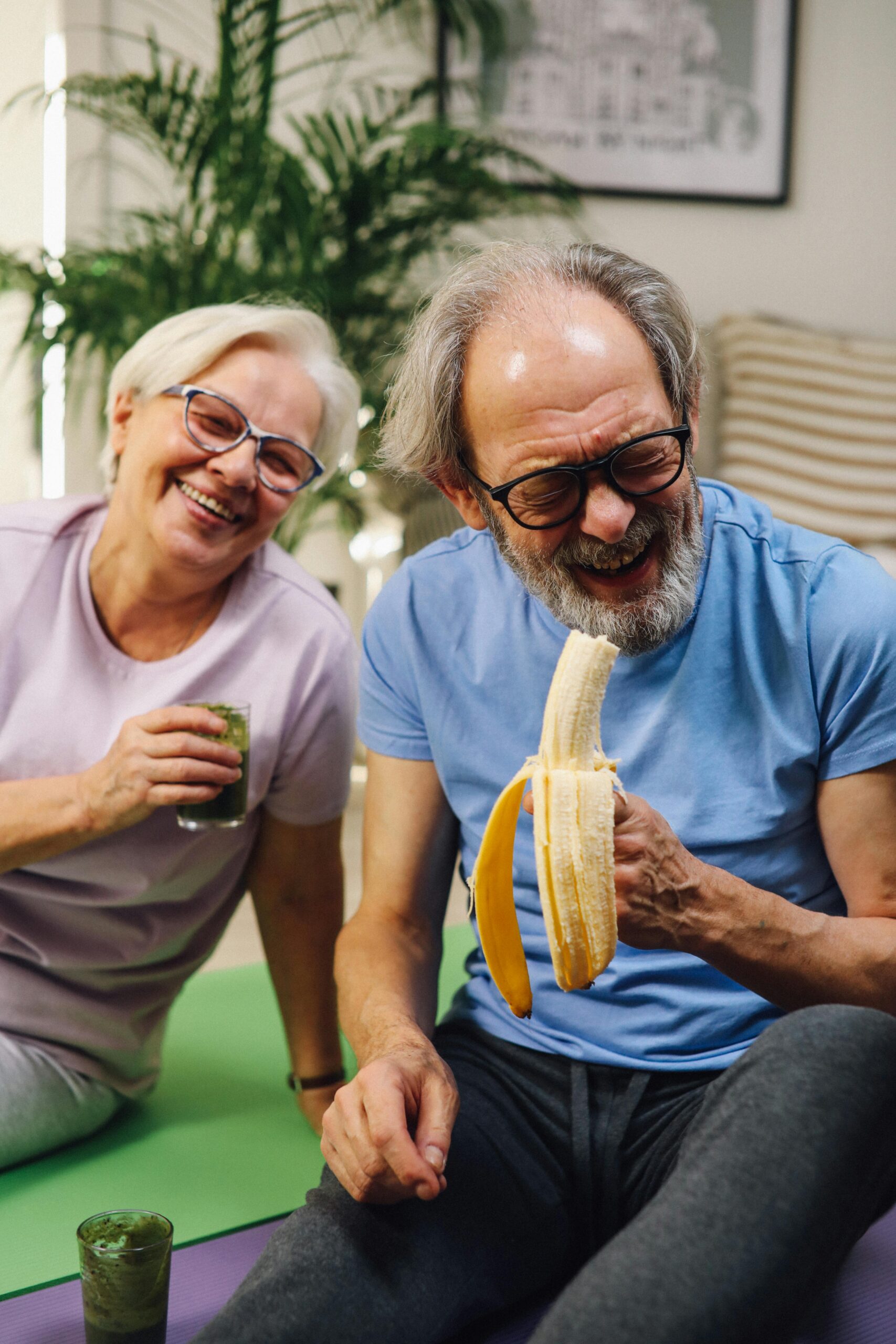 Elderly couple enjoying healthy living with fruits and smoothies indoors.
