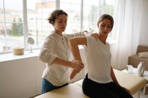 Therapist assisting woman in physical therapy session indoors with natural light.