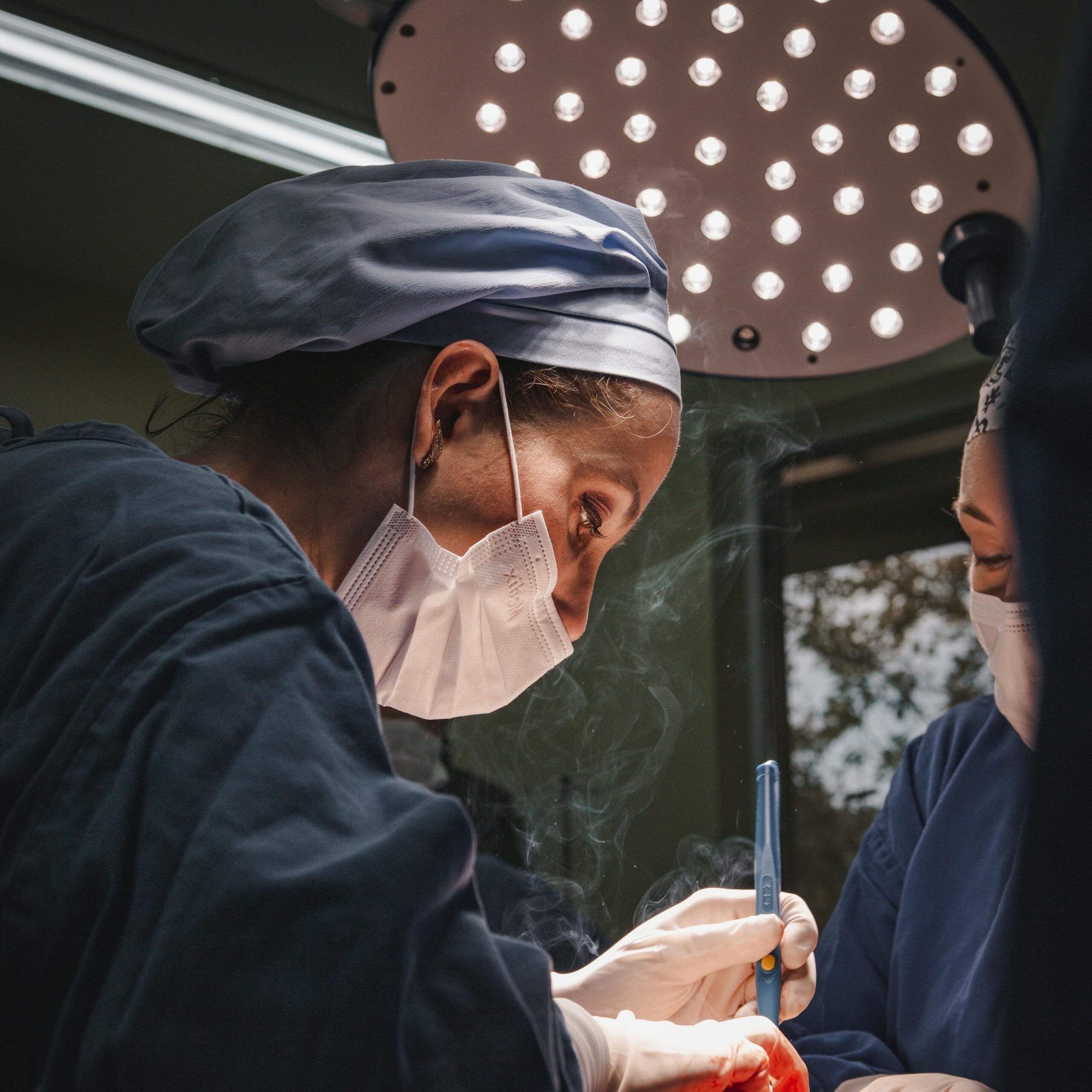 Female surgeons in SP, Brazil focusing on intricate operation under bright surgical light.