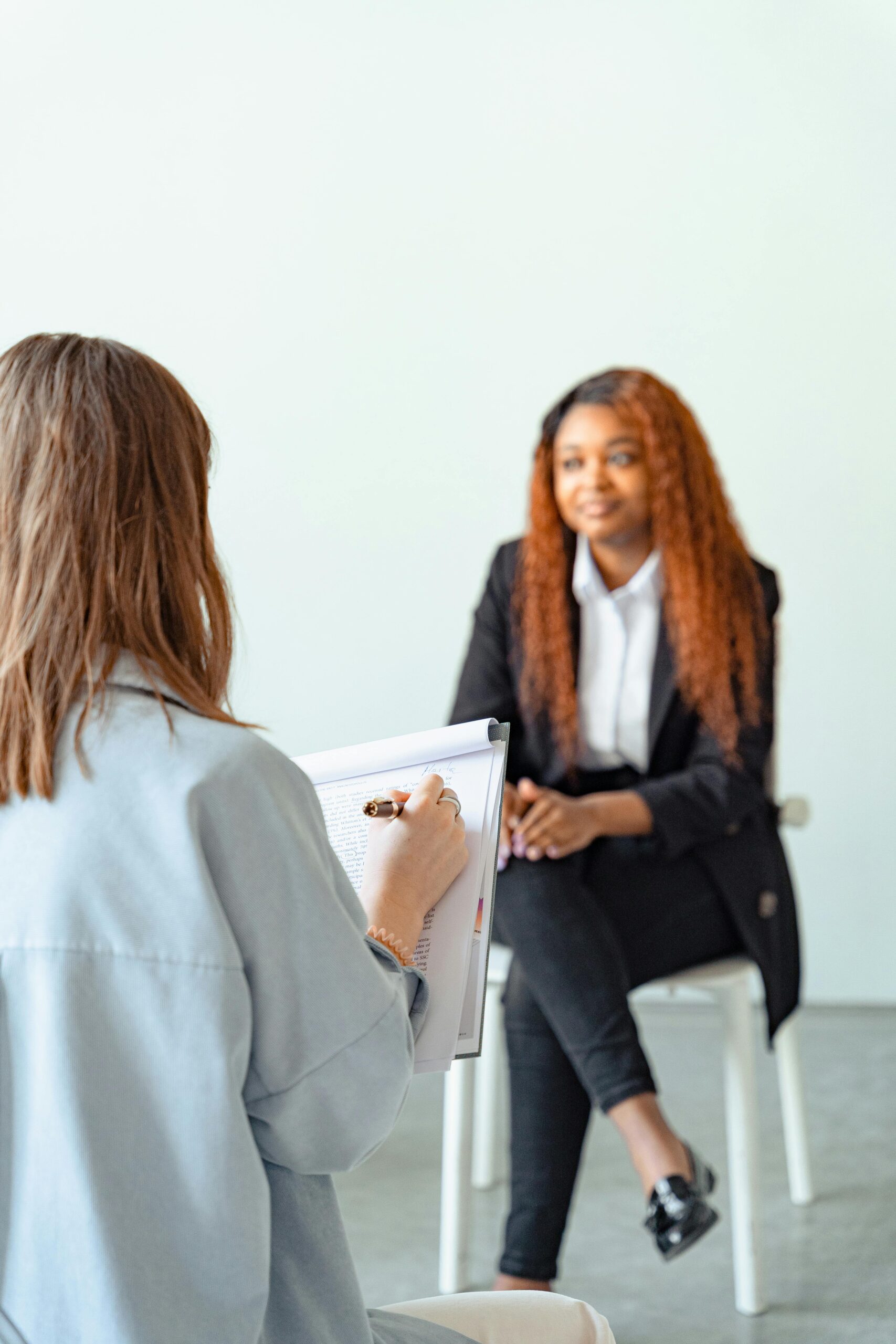 A female counselor conducts a therapy session with a client in a modern office setting.