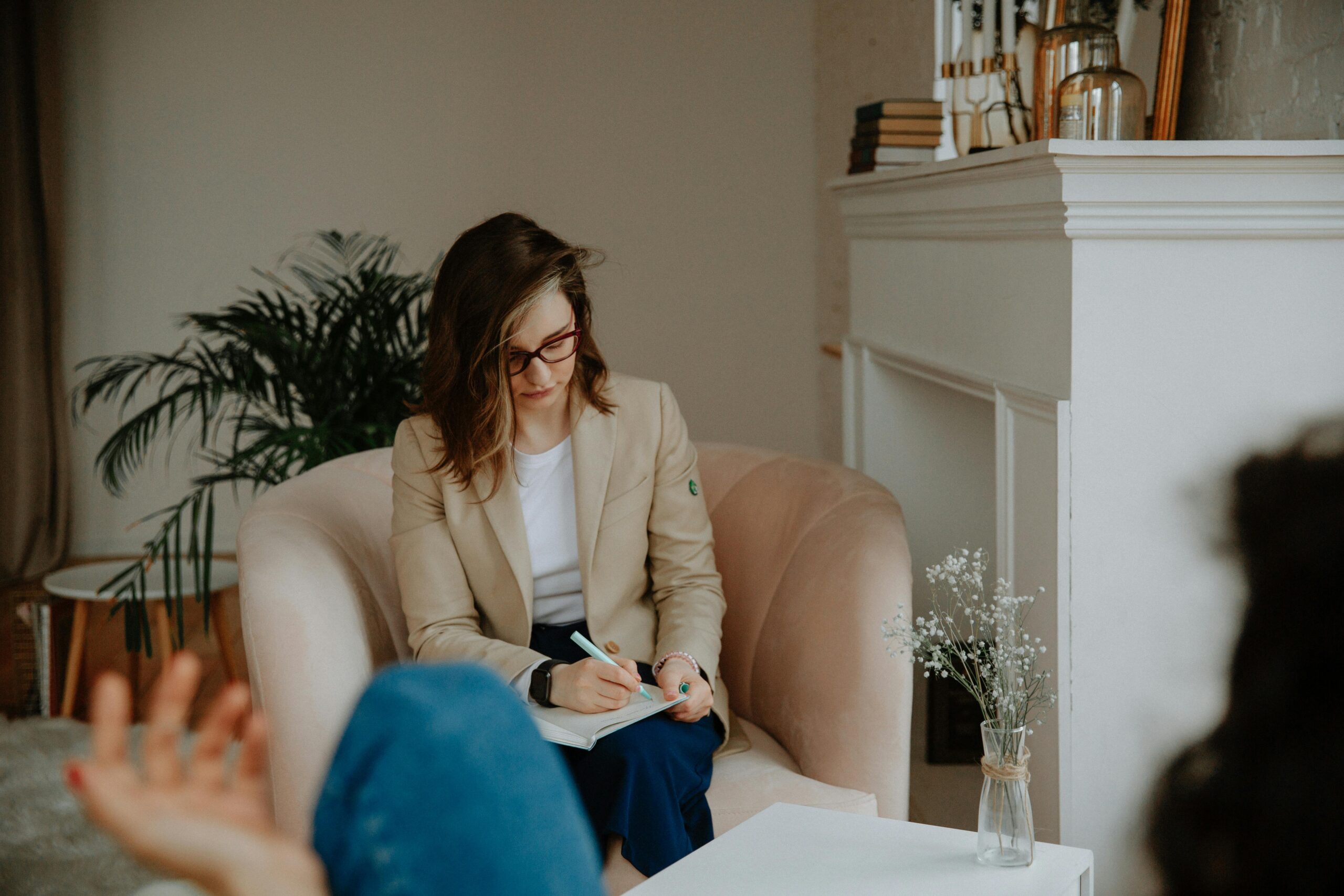 A professional therapist takes notes during a private counseling session in a cozy room.