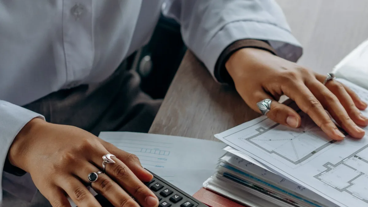 Person working through budget documents with a calculator, estimating the cost of telepsychiatry services