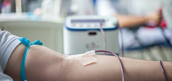 A detailed close-up of an arm during the blood donation process in a medical setting.