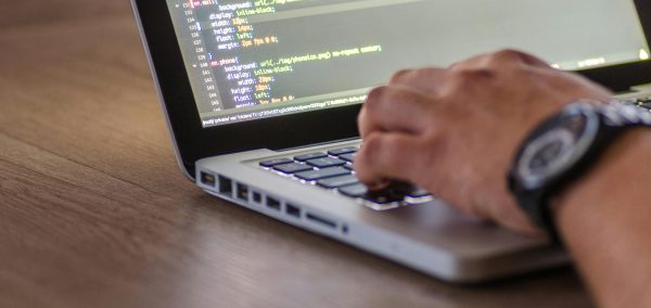 A close-up shot of a person coding on a laptop, focusing on the hands and screen.