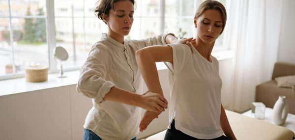 Therapist assisting woman in physical therapy session indoors with natural light.