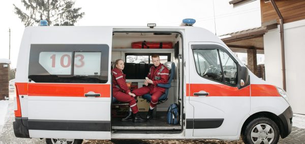 Two paramedics sitting in an ambulance parked outside on a snowy day.