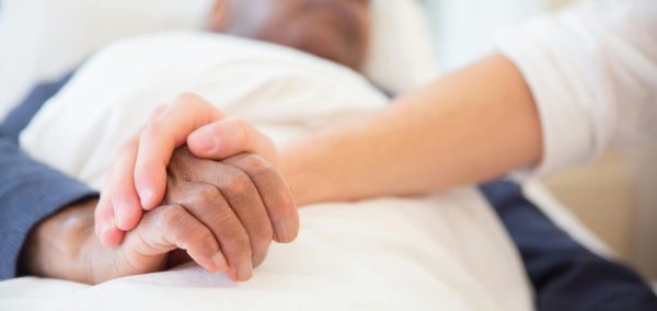 A comforting gesture as a hand holds another in a hospital setting, symbolizing care and support.