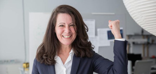 Smiling businesswoman in a smart suit celebrating a success in the office.